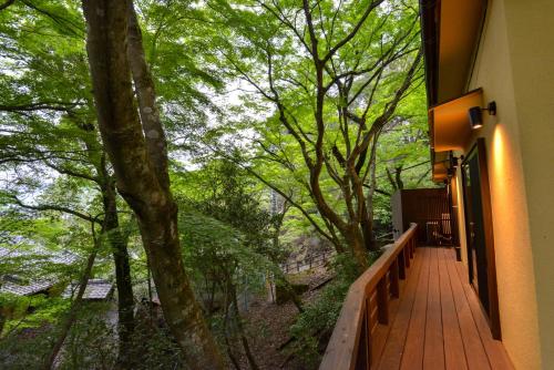 a wooden walkway with a view of a forest at Villa Hamorebi in Miyajima