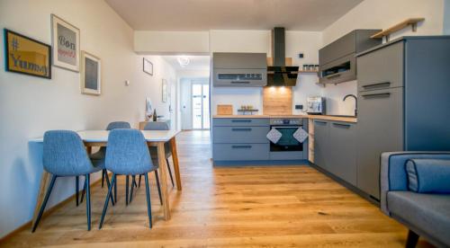 a kitchen with a dining table and blue chairs at SPA Boutique Appartement # 26 with Indoor- and Outdoorpool in Neusiedl am See