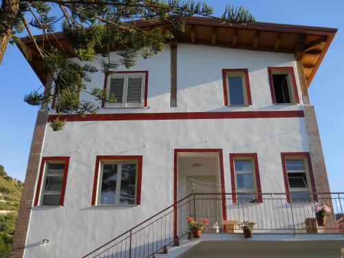 a white house with red windows and a balcony at Michelangelo's House in Gioiosa Marea