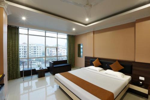 a bedroom with a large bed and a large window at Hotel Grand Luit in Guwahati