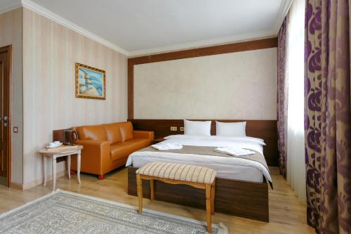 Habitación de hotel con cama y sofá en Sacvoyage Hotel en Almaty