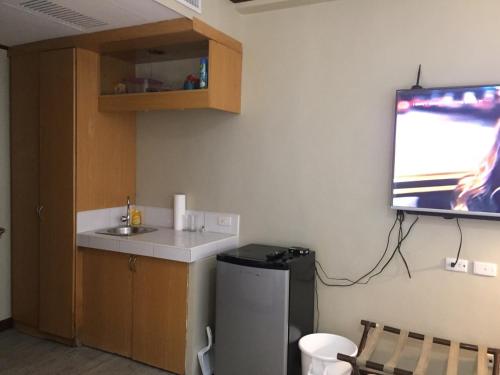 宿霧市的住宿－GOLDEN PEAK CONDO，一个带水槽的厨房和墙上的电视