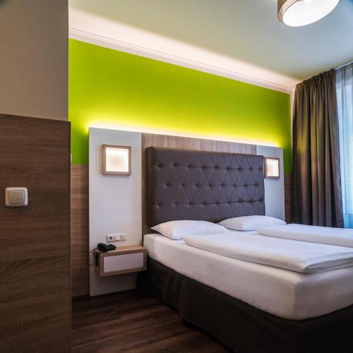 two beds in a room with a green wall at Theater Hotel Salzburg in Salzburg