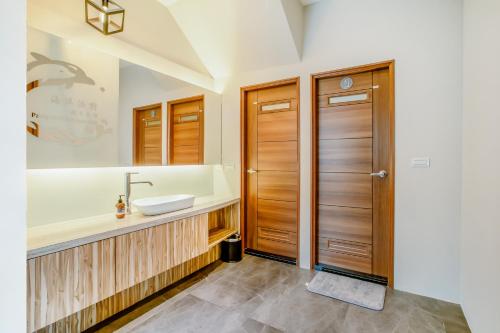baño con lavabo y puerta de madera en Party of the Ocean B&B, en Magong