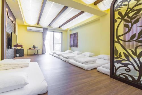 a row of white beds in a room at Party of the Ocean B&B in Magong