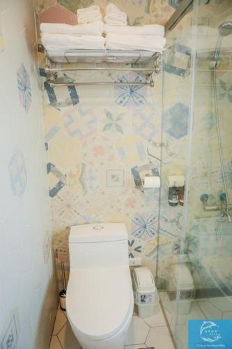 a bathroom with a toilet and a shower with towels at Party of the Ocean B&B in Magong