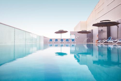 a pool with chairs and umbrellas in a building at Treppan Hotel & Suites By Fakhruddin in Dubai