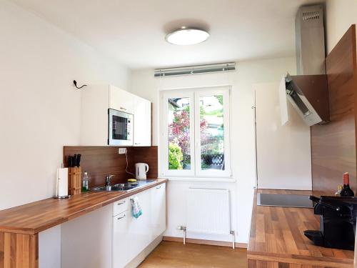 a kitchen with white cabinets and a window at Aparthotel Pan Haus in Bad Ischl