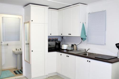 una cocina con armarios blancos y fregadero en NeverToforget Birds Haven, en Port Alfred