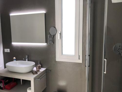 a bathroom with a white sink and a window at Padua Suite in Padova