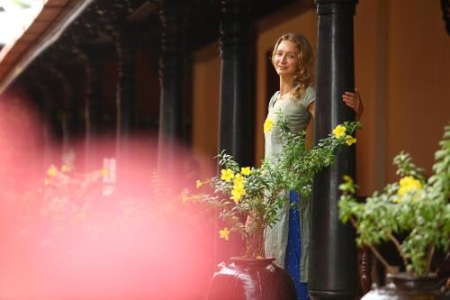 a woman standing next to a pole next to flowers at Ginger House Museum Hotel in Cochin