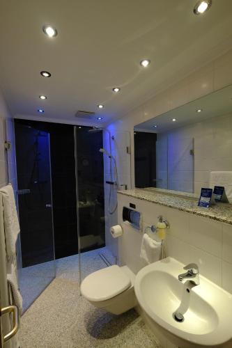 a bathroom with a toilet and a sink and a shower at Hotel Savoy Hannover in Hannover