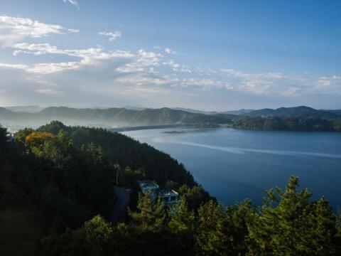 a view of a lake with a house on a hill at Asia Lakeside Hotel in Jinju