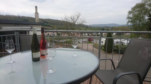 einen Tisch mit Weinflaschen und Gläsern auf dem Balkon in der Unterkunft Weingut Edwin Pauly in Palzem