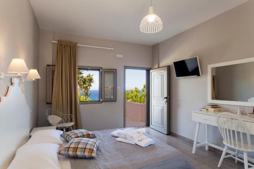 a bedroom with a bed with a desk and a window at Mythos Suites Diskos in Léntas