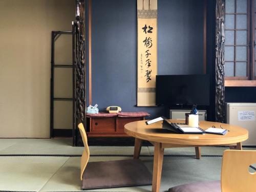 a table and a chair in a room with writing on the wall at Tabinoyado Saikawa in Kuroishi