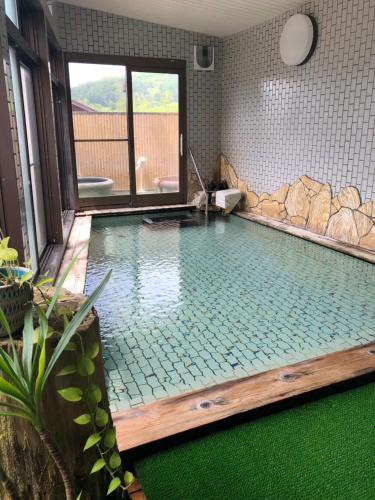 a large swimming pool in a bathroom with a tub at Tabinoyado Saikawa in Kuroishi
