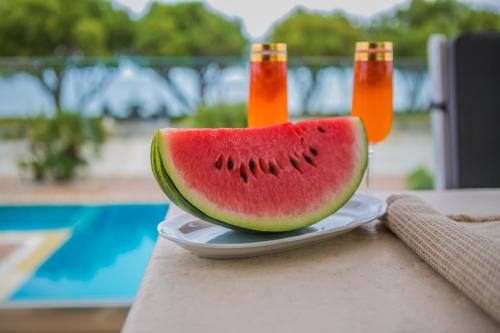 a slice of watermelon on a plate with two bottles of juice at Villa Pelagos in Koutsounari