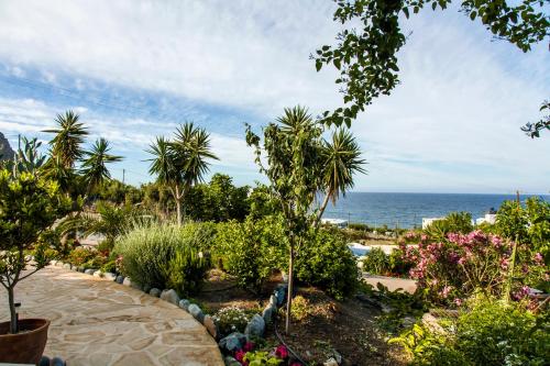 a garden with palm trees and the ocean in the background at Mythos Suites Diskos in Léntas