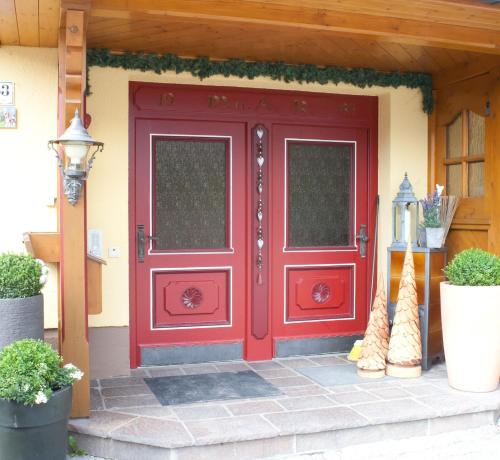 a red front door of a house with plants at Feriengut Lackenhof in Filzmoos