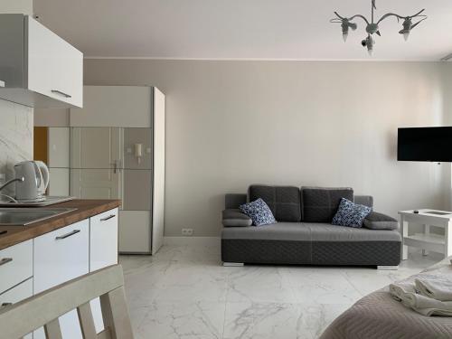 a living room with a couch and a kitchen at Apartament Sloneczny in Kołobrzeg