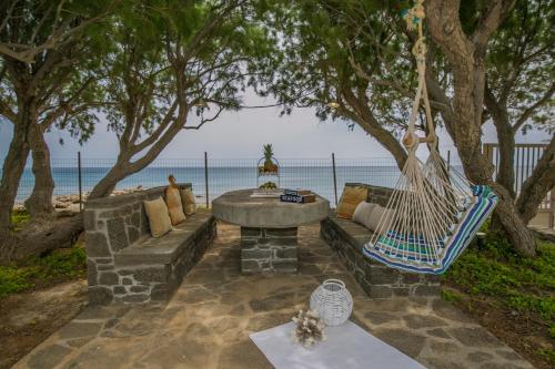 a patio with a couch and a hammock and the ocean at Villa Pelagos in Koutsounari