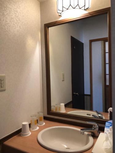a bathroom with a sink and a large mirror at Tabinoyado Saikawa in Kuroishi