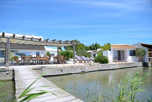 a house with a wooden bridge over a body of water at Maison l'Etrier in Saintes-Maries-de-la-Mer