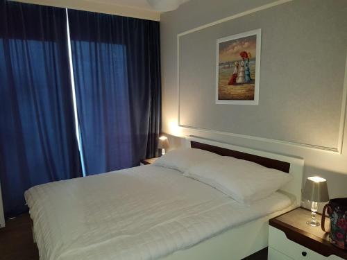1 dormitorio con cama blanca y cortinas azules en u Jolanty, en Jastrzębia Góra