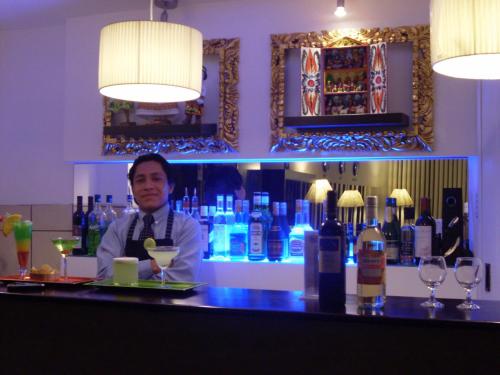 a man standing behind a bar in a room with bottles at CasaHotel Jockey Plaza Mall in Lima