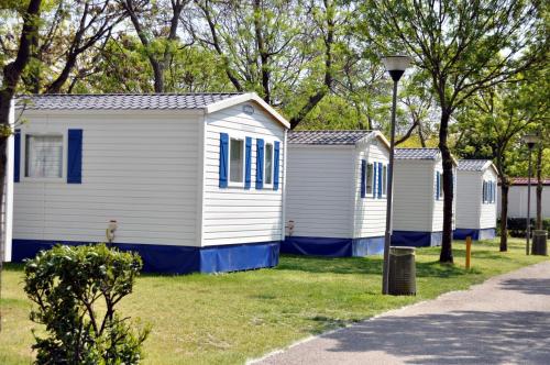 a row of white houses with blue windows at Camping Village Città di Milano in Milan