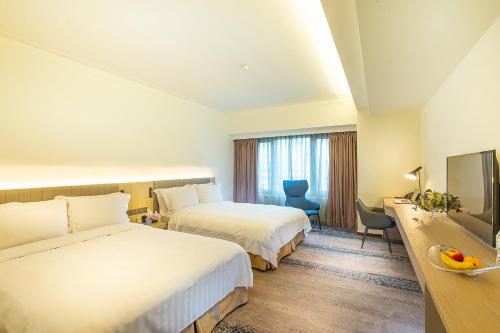 a hotel room with two beds and a television at Howard Plaza Hotel Hsinchu in Hsinchu City