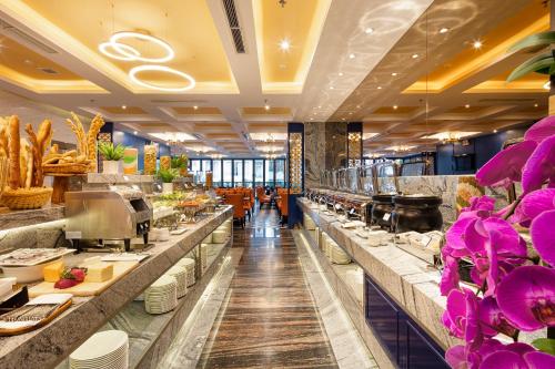 a restaurant with a buffet line with purple flowers at Erica Nha Trang Hotel in Nha Trang