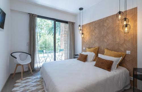 ein Schlafzimmer mit einem großen weißen Bett und einem Fenster in der Unterkunft SINFONIA in Saint-Tropez