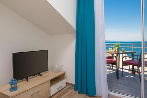 salon z telewizorem i balkonem ze stołem w obiekcie The Beach Suites w mieście Jesenice