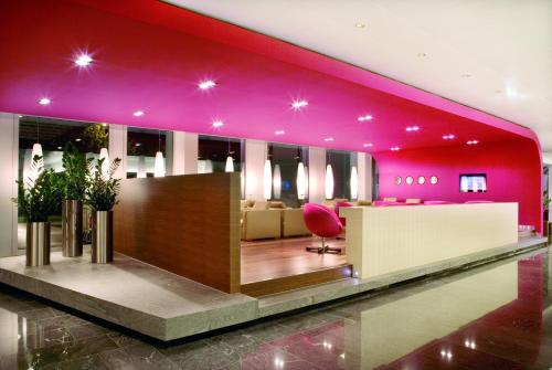 un vestíbulo con una pared rosa y una silla rosa en Mövenpick Hotel Zurich Airport en Glattbrugg