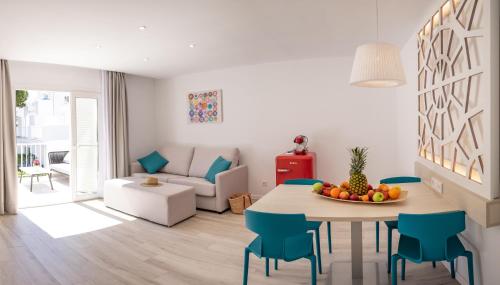 a white living room with a table and chairs at Hotel Club Es Talaial in Cala d´Or