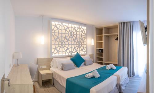 een hotelkamer met 2 bedden en een raam bij Hotel Club Es Talaial in Cala d´Or