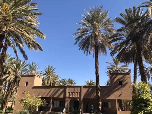 a building with palm trees in front of it at Maison d Hôte Ighrem in Goulmima