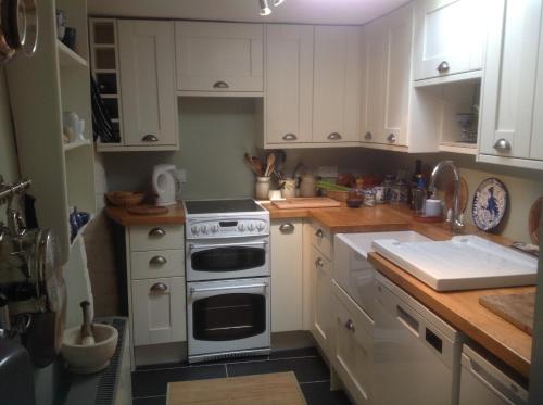 uma cozinha com armários brancos e um forno com placa de fogão em Jasmine Cottage em Lerryn
