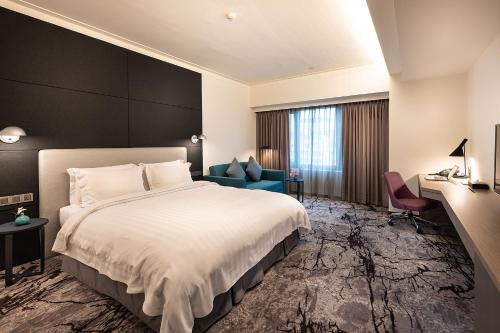 Habitación de hotel con cama y silla azul en Howard Plaza Hotel Hsinchu en Hsinchu City