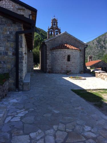 an old stone building with a church in the background at Rent House Orahovo in Virpazar