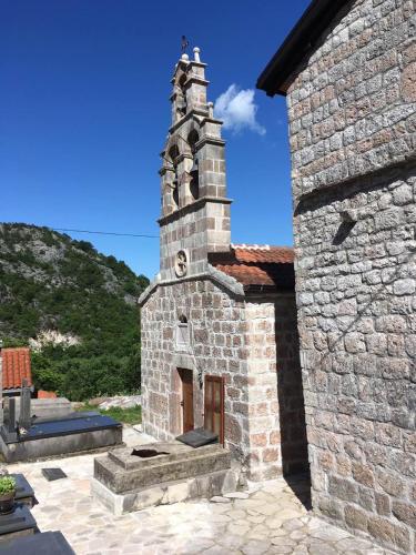 a small brick building with a clock tower on it at Rent House Orahovo in Virpazar