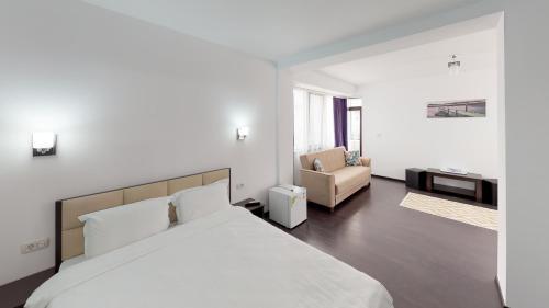 a white bedroom with a bed and a chair at Matei Mamaia-Nord in Mamaia Sat/Năvodari