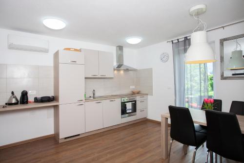 a kitchen with white cabinets and a table with chairs at Apartments Razingar 9 in Bled