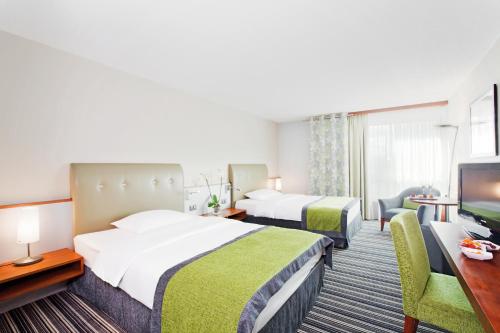 a hotel room with two beds and two lamps at Mövenpick Hotel Zurich Airport in Glattbrugg