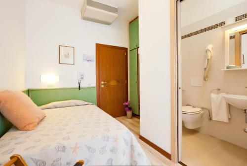 a bedroom with a bed and a sink and a toilet at Hotel Excelsior in Caorle