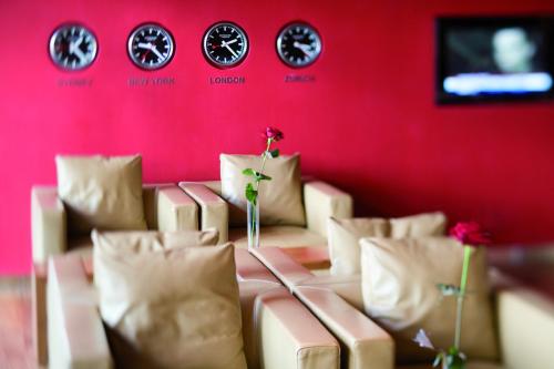 a room with a red wall with couches and flowers at Mövenpick Hotel Zurich Airport in Glattbrugg