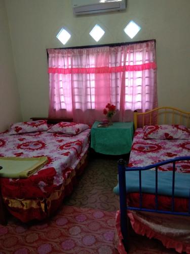 a bedroom with two beds and a window at Homestay Damai Sri Kota in Kepala Batas