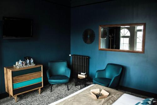 a bedroom with two blue chairs and a bed and a mirror at La villa 10 HÔTEL SPA in Étretat